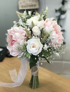 a bouquet of flowers sitting on top of a wooden table next to a white ribbon