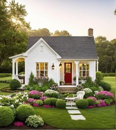 a white house with flowers and bushes around the front door is surrounded by greenery