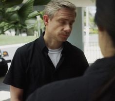 a man in black shirt talking to another person