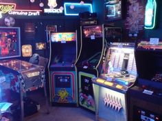 several arcade machines in a room with neon signs