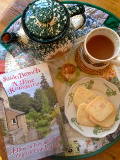 a cup of tea and some cookies on a plate with a book next to it