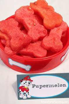 a red bowl filled with dog treats next to a sign