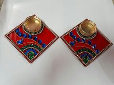 pair of red and blue earrings with gold accents on white surface, close up view