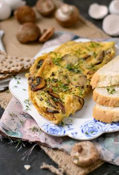 an omelet with mushrooms and bread on a plate next to some crackers