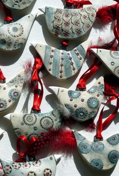 several ornaments are arranged on a white surface, with red ribbons and beads hanging from them