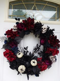 a wreath with skulls and flowers is hanging on the front door to decorate it for halloween