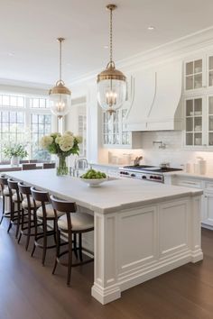 a large kitchen with white cabinets and an island in the middle, surrounded by wooden flooring