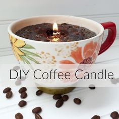 a coffee mug with a candle in it surrounded by coffee beans