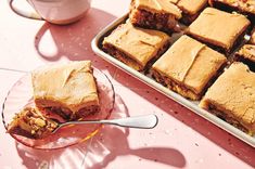 a table topped with lots of desserts next to a pan filled with cakes and muffins