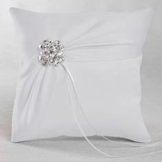 a white pillow with a crystal brooch on the side and ribbon down the middle