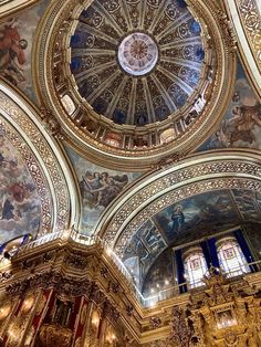 an ornate ceiling with paintings and chandeliers in a church or cathedral, looking up at the dome