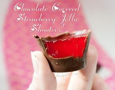 chocolate covered strawberry jelly shooters in the palm of someone's hand with text overlay