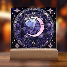 a card with a purple moon and stars in the center on a wooden stand against a blurry background