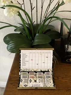 a wooden table topped with a vase filled with white flowers and lots of writing paper