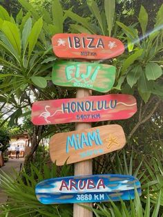 a wooden sign with many different colored signs on it's side in front of some trees