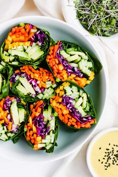 a white bowl filled with lettuce and veggies next to dipping sauce