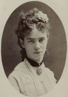 an old black and white photo of a young woman with curly hair wearing a necklace