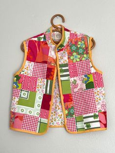 a child's quilted vest hanging on a wall with a wooden hanger