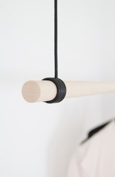 a baseball bat hanging from a black cord on a white wall with a person in the background