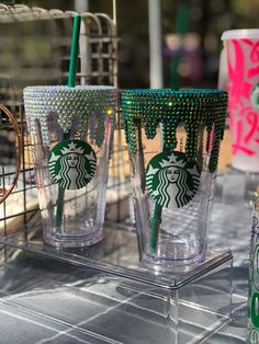 three starbucks cups sitting on top of a table next to a cup holder with two straws in it