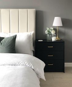 a white bed sitting next to a night stand with two lamps on top of it