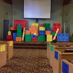 there are many lego blocks on the floor in front of a projector screen and some chairs