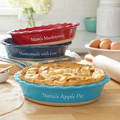 three pies sitting on top of a wooden table next to bowls and utensils