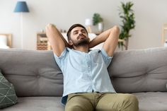 a man sitting on a couch with his hands behind his head