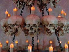 there are many candles and skulls hanging from the wall in front of them on chains