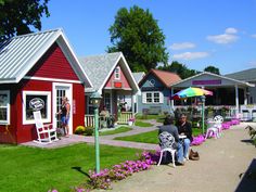 people are sitting on lawn chairs in front of small houses with red and white sidings