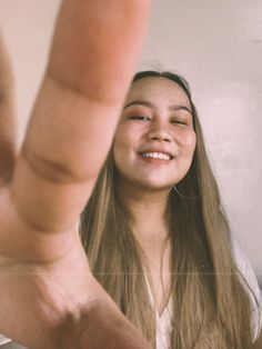 a girl is smiling and holding her hand up