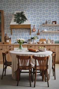 a kitchen with blue and white wallpaper, wooden cabinets and table surrounded by chairs