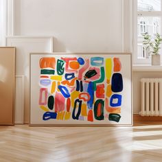 an abstract painting is displayed on the floor in front of a radiator and window