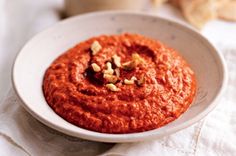 a white bowl filled with red sauce and nuts