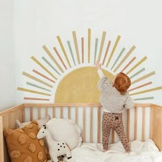 a little boy that is standing in a crib with some stuffed animals on it