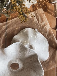 two white vases sitting on top of a wooden table