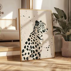 a framed photograph of a leopard sitting on the floor next to a potted plant