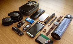 an assortment of personal items laid out on a wooden floor next to a cell phone