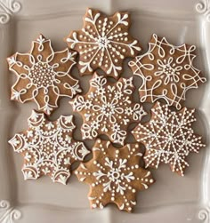 several decorated cookies on a white plate with snowflakes and swirly icing