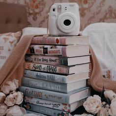 a camera sitting on top of a stack of books next to a pile of flowers