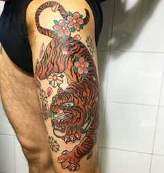 a man with a tiger tattoo on his arm standing in front of a tiled wall