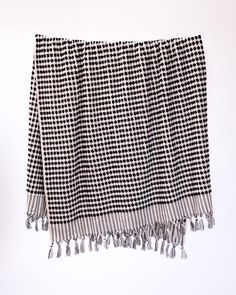 a black and white checkered blanket hanging on a wall with tassels around it