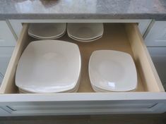 three white plates are sitting in an open drawer