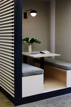 a table and bench in a room with blinds on the wall behind it, next to a potted plant