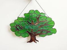 a stained glass tree hanging from a chain on a white wall with chains around it