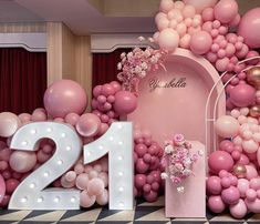 balloons and flowers decorate the entrance to a 21st birthday party with pink, white and gold decorations