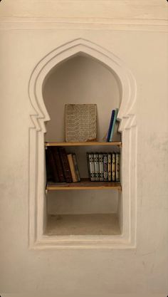 a book shelf with books on top of it in a room that has white walls