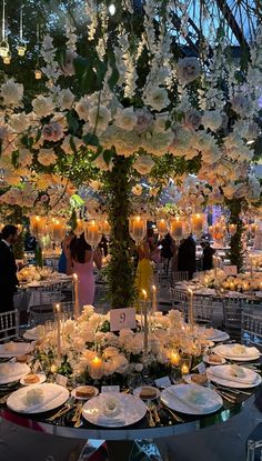 the table is set up for an event with flowers and candles on it, as well as people in formal wear