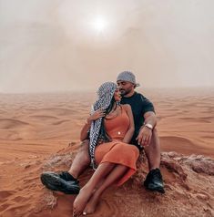 a man and woman sitting on top of a desert