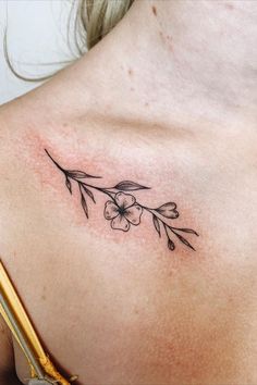 a woman's back with a flower tattoo on her left shoulder and an arrow in the middle